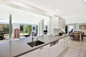 a kitchen with white cabinets and a dining room at Floriel - By Berry Getaways in Berry