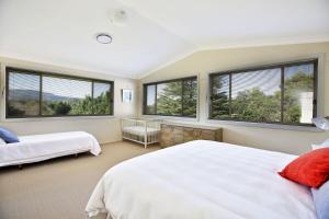 a bedroom with two beds and large windows at Floriel - By Berry Getaways in Berry +32 photos