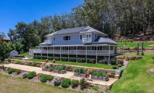 a large blue house with a garden in front of it at Possum Gully Lodge -By Berry Getaways in Berry