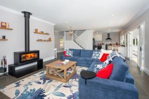 a living room with a blue couch and a fireplace at Possum Gully Lodge -By Berry Getaways in Berry +16 photos