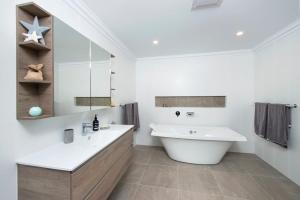 a bathroom with a large white tub and a sink at Possum Gully Lodge -By Berry Getaways in Berry