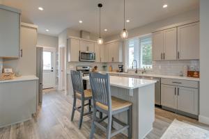 a kitchen with white cabinets and a island with bar chairs at The Ginger Pearl in Ocean Shores