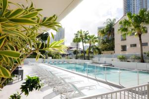 a pool on the roof of a building with chairs and trees at Trilogy Surfers Paradise in Gold Coast