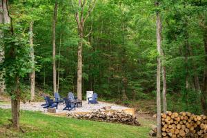 un grupo de sillas azules y una pila de troncos en White Pines Lodge- Wooded Retreat, en Cub Run