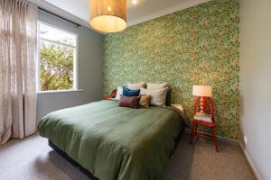 a bedroom with a green bed and a window at Mabel's Cottage - By Berry Getaways in Berry