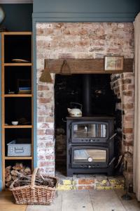 a brick fireplace with a stove in a room at Mabel's Cottage - By Berry Getaways in Berry