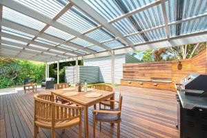 a patio with a table and chairs on a wooden deck at Rosemill Cottage - By Berry Getaways in Berry