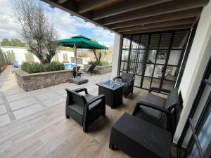 a patio with chairs and tables and an umbrella at Casa Frida con Piscina Privada Caliente, Aire Acondicionado, Billar, Parrilla & FirePit in San Miguel de Allende +49 photos