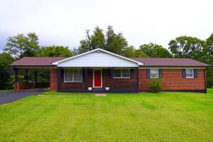 a red brick house with a red door and a yard at Spacious Pet Friendly Home in Martinsville