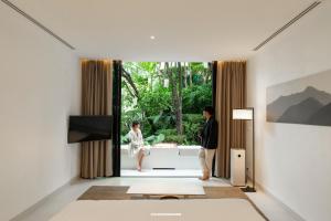a living room with two people looking out the window at K Maison Lanna Boutique Hotel-SHA Plus Certified in Chiang Mai