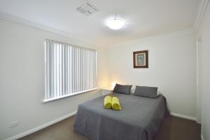 a bedroom with a bed with two yellow shoes on it at Villa Palazzo 3 - Kalbarri, WA in Kalbarri