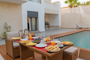 a table with food and drinks on it next to a pool at Villa Sable de Mirleft Luxury Apartment in Mirleft