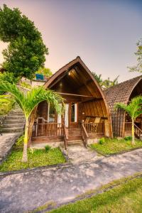 Un complejo turístico con techo de paja y palmeras. en Butterfly Bungalow, en Nusa Penida 22 fotos más