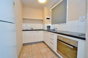a kitchen with white cabinets and a refrigerator at Riverview Holiday Apartment 49 - Kalbarri WA in Kalbarri