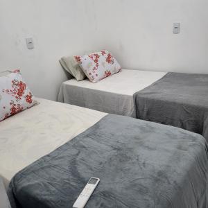 a room with three beds with a remote control at Noite hotel sul aeroporto in Palmas