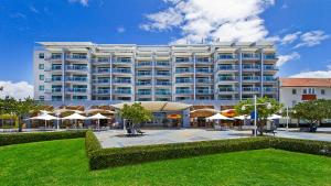 Un gran edificio blanco con sombrillas delante. en The Entrance Waterfront Apartment 302, en The Entrance