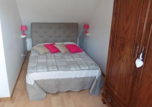 a small bedroom with a bed with two pink pillows at Chez Fred in Boursault