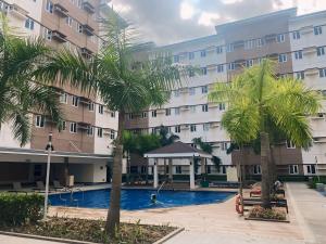 a hotel with a swimming pool in front of a building at Anne's Place at Hope Residences - SMDC Condo Beside SM Trece in Trece Martires