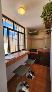 a kitchen with a counter and two stools in it at Departamento céntrico in Zacatecas