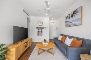 a living room with a blue couch and a tv at Executive Beachside Getaway in Maroochydore