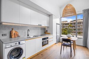 a kitchen with a washing machine and a table at Executive Beachside Getaway in Maroochydore