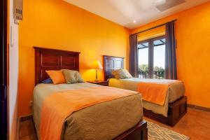 due letti in una stanza con pareti arancioni di Luxury Condo Steps Away from Downtown San Miguel a San Miguel de Allende
