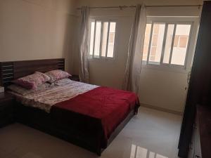 a bedroom with a bed with a red comforter and two windows at Private room for ladies near metro in Dubai