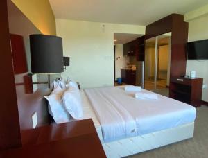 a hotel room with a large bed with white pillows at COZY Studio at Ming Garden Residence in Kota Kinabalu