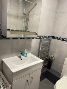 Un baño blanco con lavabo y espejo. en Cosy Room4 in London Kings Cross, en Londres 2 fotos más