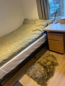Una cama en una habitación con un escritorio y una alfombra. en Cosy Room4 in London Kings Cross, en Londres