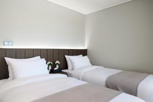 a row of three beds in a room at The Hotel Sokcho in Sokcho +25 photos