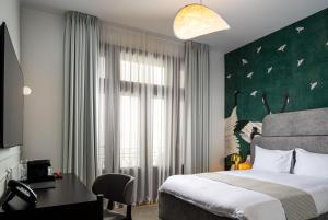 a hotel room with a bed and a desk and a window at Ecletico Villa in Bucharest