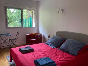 een slaapkamer met een rood bed en 2 handdoeken erop bij Vue sur jardin, 3 pièces in Parijs
