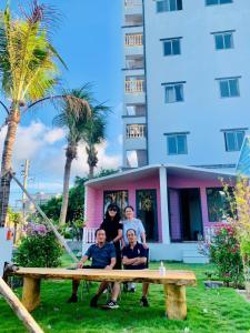 Eine Gruppe von Menschen sitzt an einem Picknicktisch vor einem Gebäude in der Unterkunft An Phú Villa in Cu Lao Thu