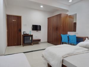 a bedroom with two beds and a desk and two blue chairs at DatsunG Studios Near Pune Airport in Pune