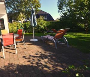a group of chairs and an umbrella on a patio at Reethäuser 17 Fam Kröning in Groß Zicker