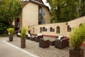 un patio con sillas y árboles frente a un edificio en H+ Hotel Nürnberg en Núremberg