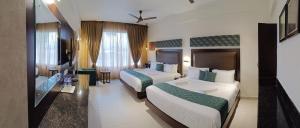 una camera d'albergo con due letti e una televisione di Hotel Rameswaram Grand a Rāmeswaram