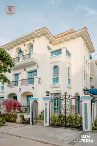 une maison blanche avec des fenêtres bleues et un portail dans l'établissement Sun Villa 7 br & pool, à Hạ Long
