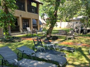 a group of chairs sitting in the grass in front of a building at Mopani Lodge Victoria Falls in Victoria Falls