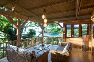 un porche cubierto con sillas y mesa de cristal en Castara Retreats, en Castara