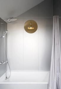 クラマールにあるMaison d'architecte à 7 minutes en train de Parisの浴槽の上に照明が付いたシャワー付きのバスルーム
