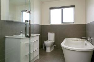 a bathroom with a toilet and a sink and a tub at Tempting on Tui - Private home near Taupo CBD in Taupo +9 photos