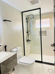 a white bathroom with a toilet and a shower at AL HUWAILAT 3 BED ROOM DELUX APPARTMENT b in Al Jubail +10 photos