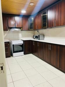 a kitchen with wooden cabinets and a white tile floor at AL HUWAILAT 3 BED ROOM DELUX APPARTMENT b in Al Jubail