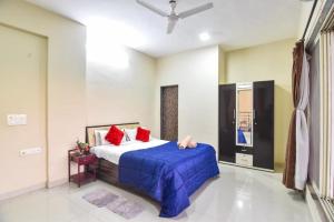 Schlafzimmer mit einem Bett mit blauer Bettwäsche und roten Kissen in der Unterkunft 4BHK VERONICA VILLA by Welcome Stays in Lonavla