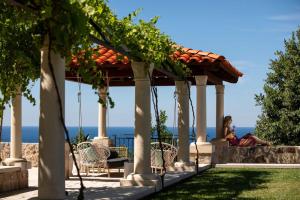 a woman sitting on a swing under a gazebo at Palace Natali in Dubrovnik