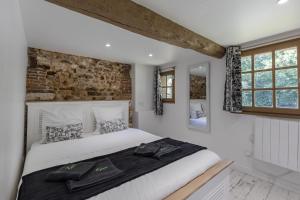 a bedroom with a white bed and a brick wall at La Petite Normande - Ressourçante - Nature in Foulbec