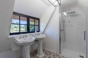 a white bathroom with two sinks and a shower at La Petite Normande - Ressourçante - Nature in Foulbec +14 photos