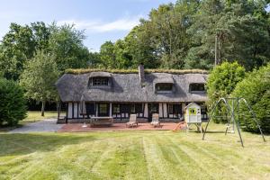 a house with a thatched roof with a playground at La Petite Normande - Ressourçante - Nature in Foulbec